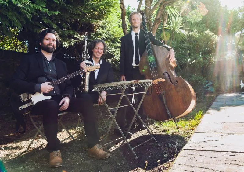 three musicians in suits holding their instruments