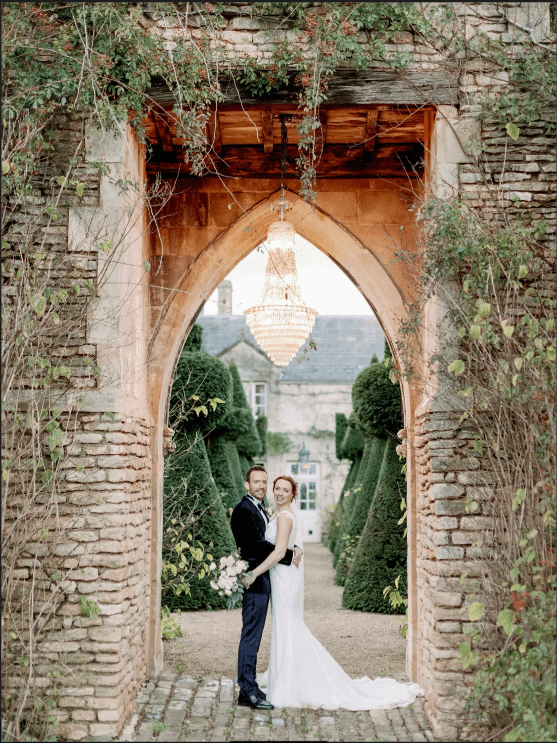 bride and groom hugging under a flowered filled arch