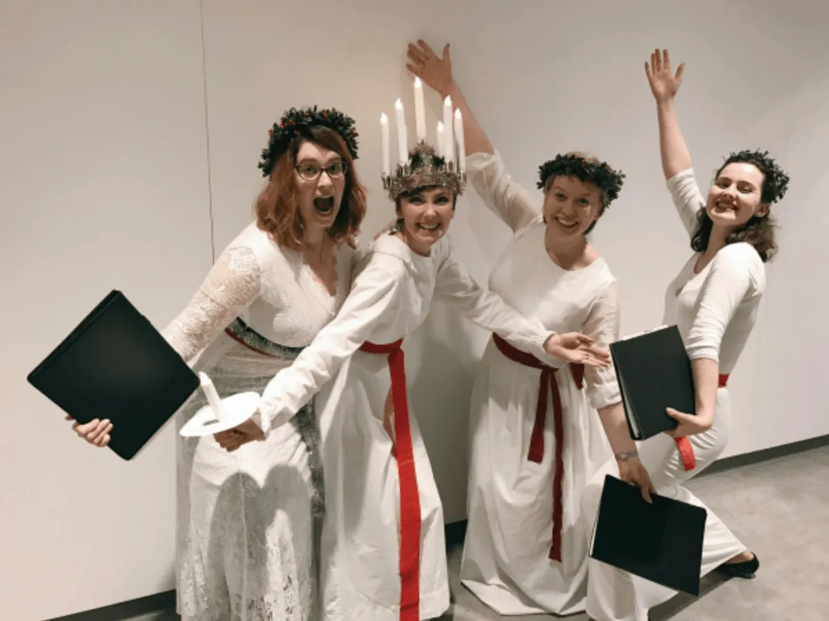 four carol singers dressed in christmas themed costumes posing|