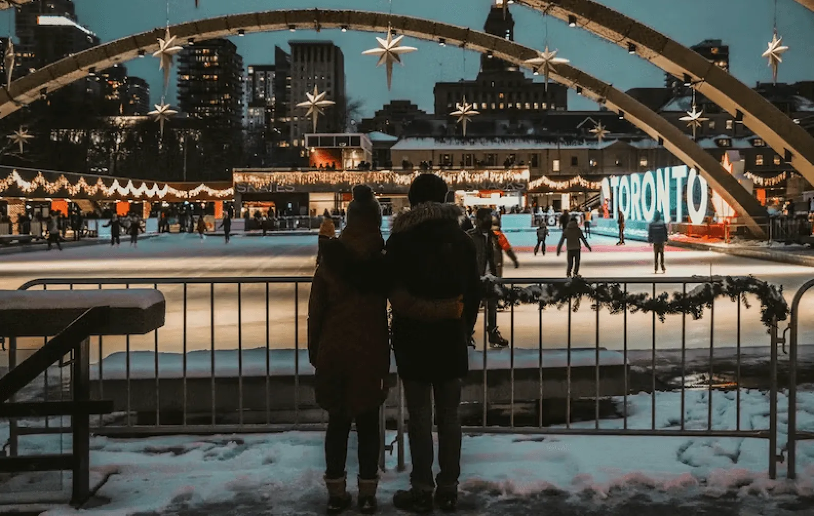 two people standing infront of a ice skating rink at dusk