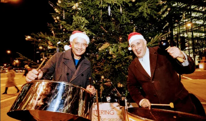 two steel drummers in Christmas hats smiling