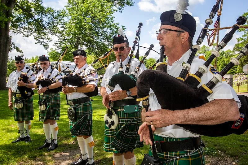 group of bagpiper players playing in ceremonial attire