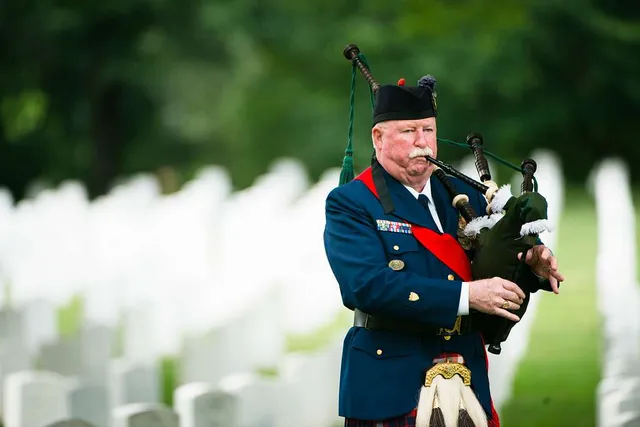 bagpiper playing a graveyard in full ceremonial attire
