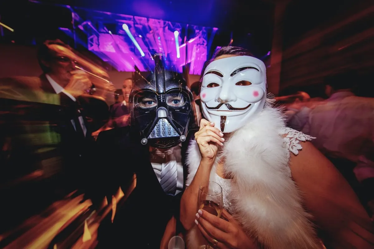 costume party with two women dressed as V is for Vendatta and Darth Vader