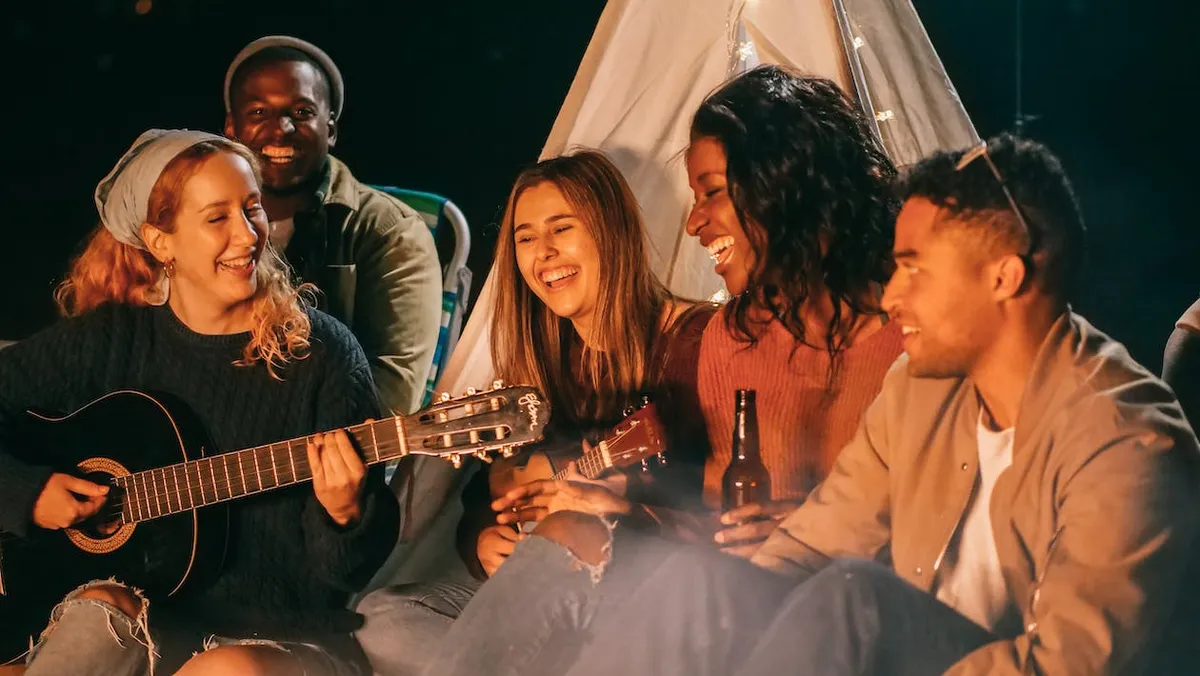 group of friends singing around a campfire
