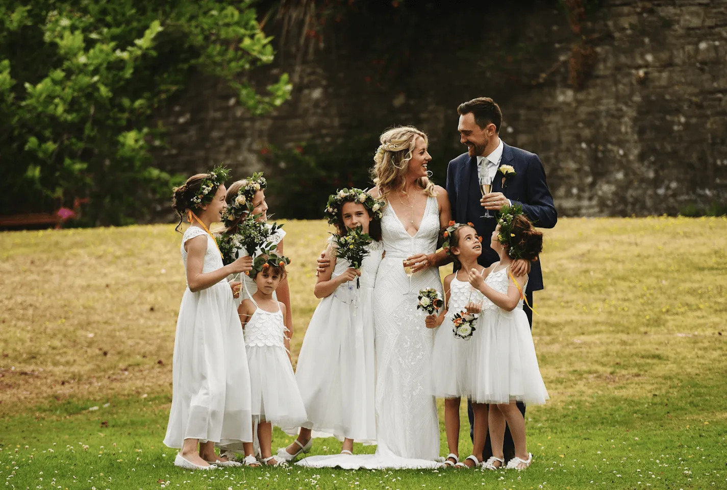 bride and groom having their photo taken with their daughters in a field