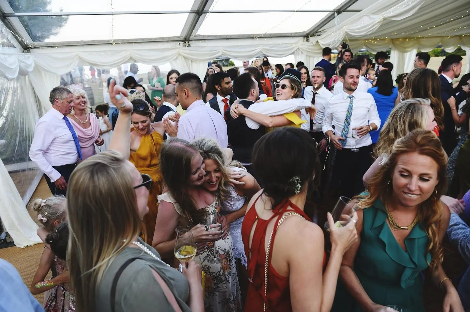 Aerial photo of wedding reception party with everyone dancing and couple in the foreground hugging