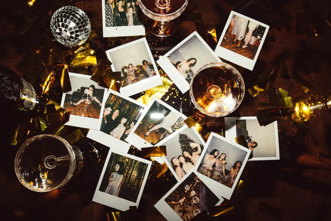 a group of polaroid photos on a dark wooden table with mini disco balls and glitter