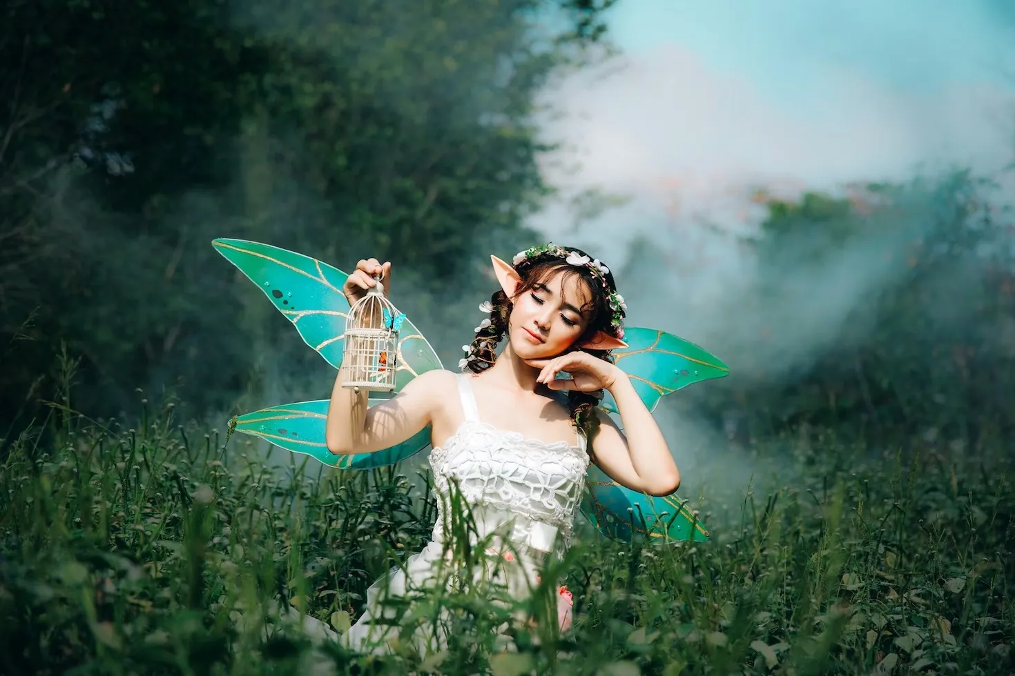 woman dressed as a fairy holding a lantern in a long grass field