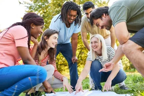 group of young people looking at a map in a garden and having fun
