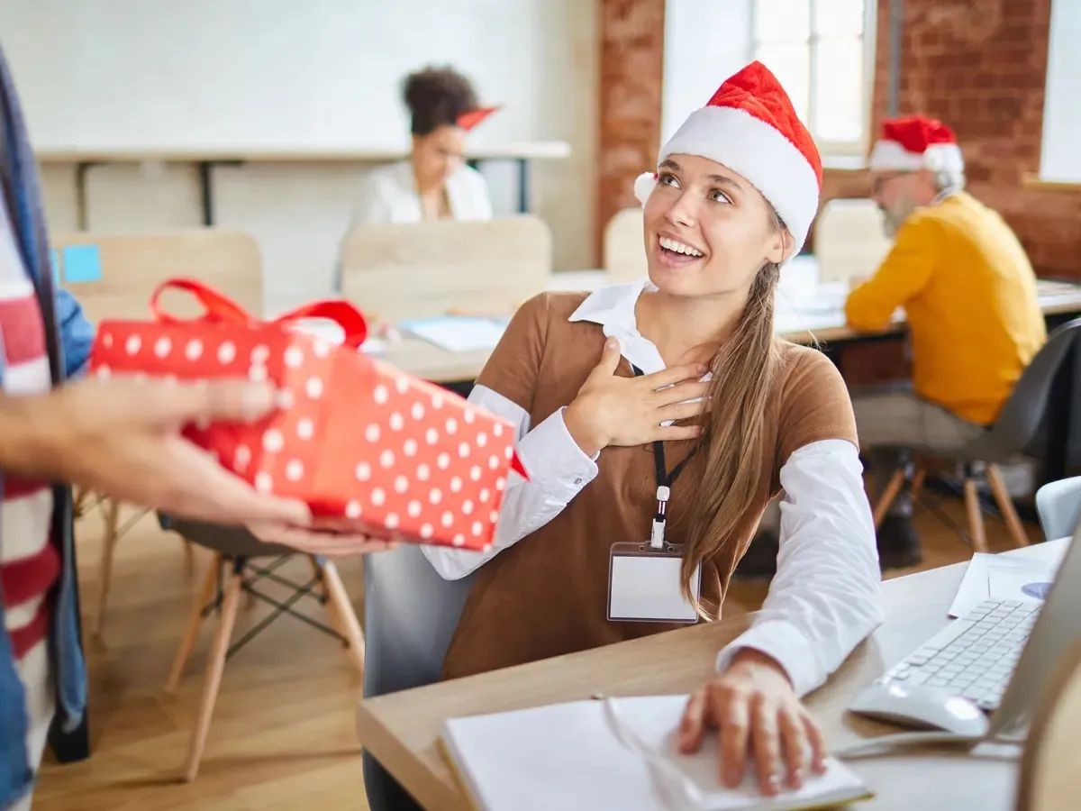 woman being presented a gift for secret santa in an office