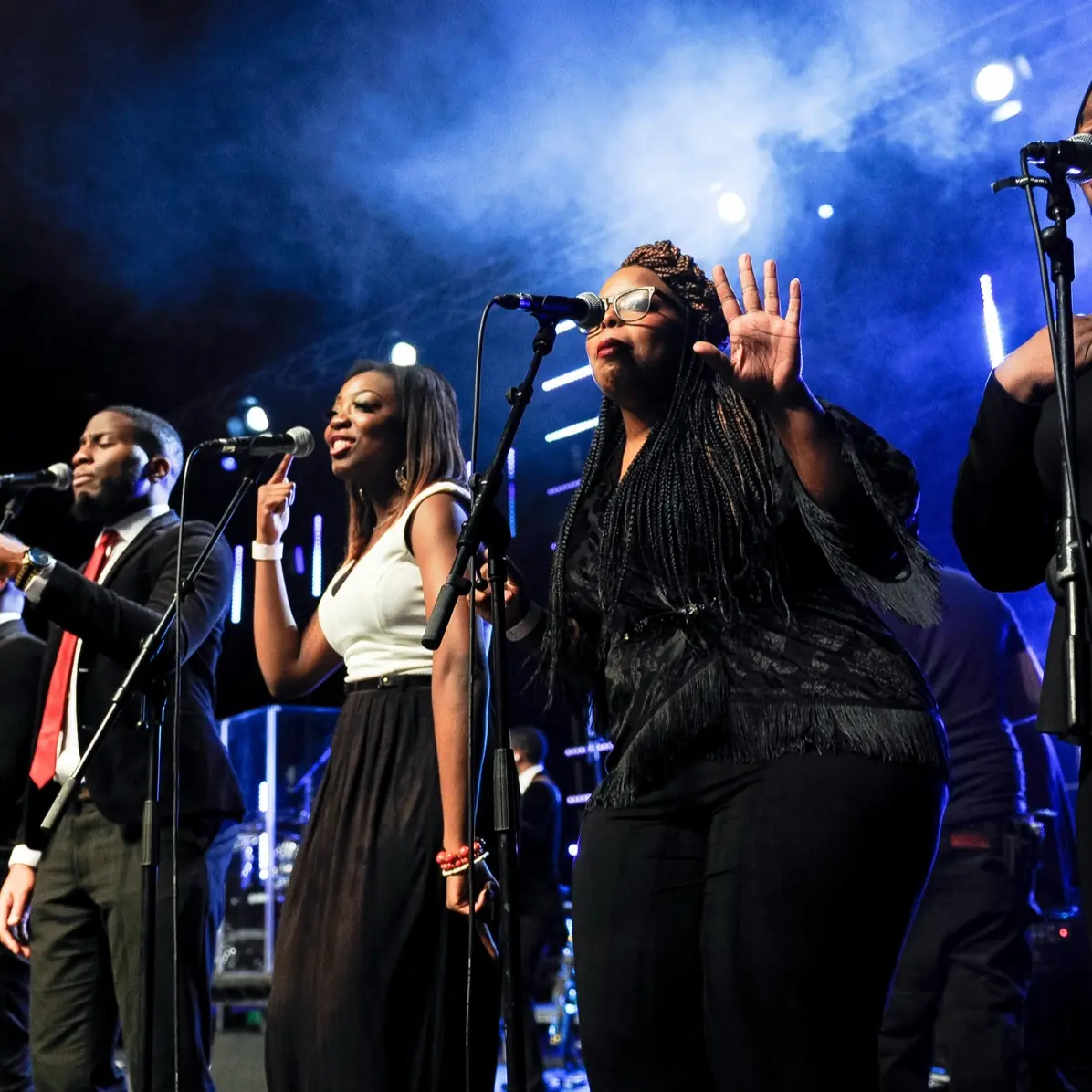 A gospel choir singing on stage under blue lights